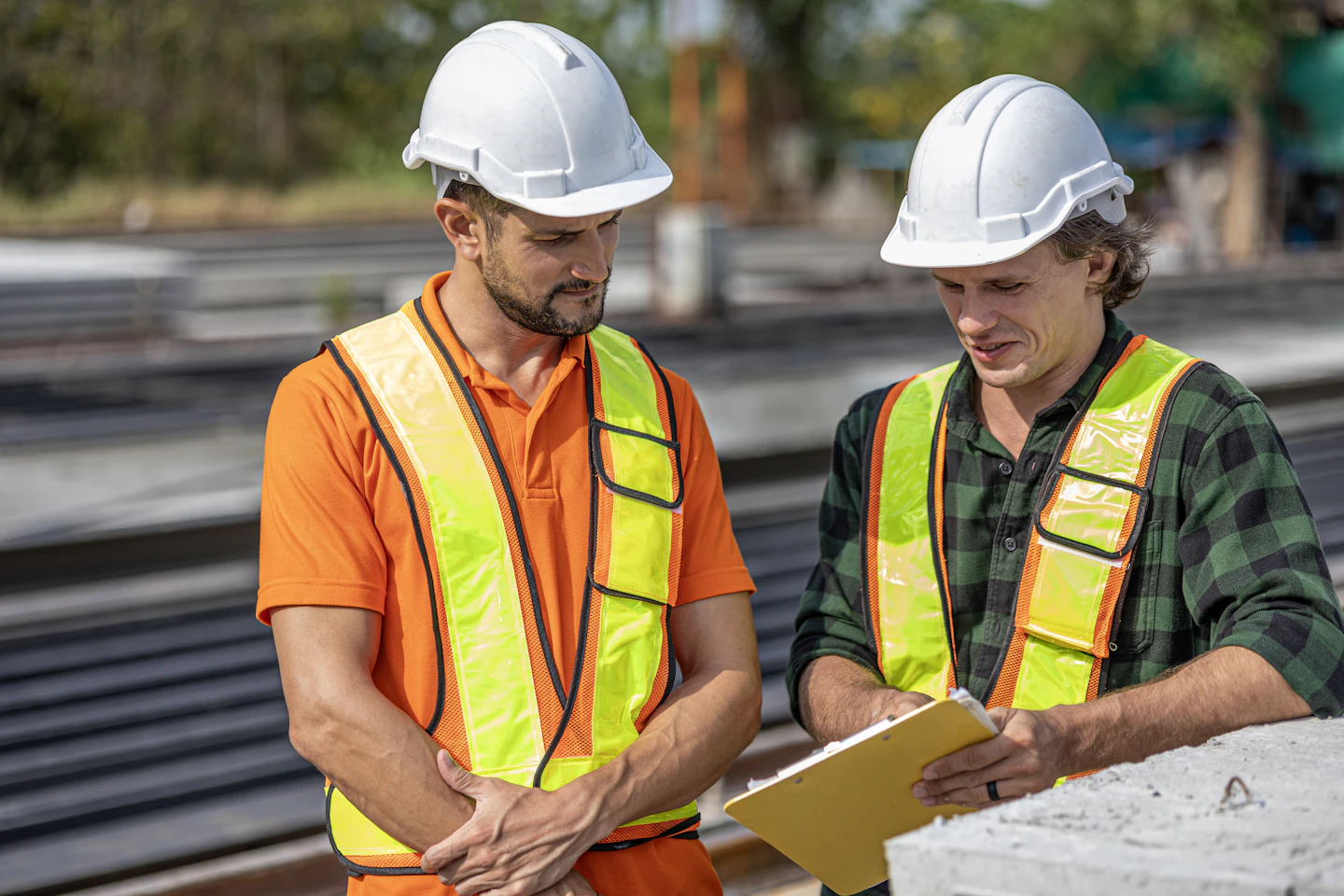 Deux ouvriers en tenue de chantier consultent un support de suivi lors d'une réception de travaux
